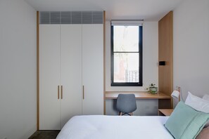 A bedroom with a bed, a desk, and a wardrobe.