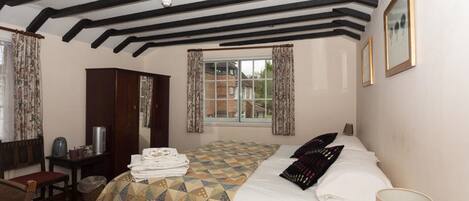 A bedroom with a bed, a desk, a chair, and a window with curtains.