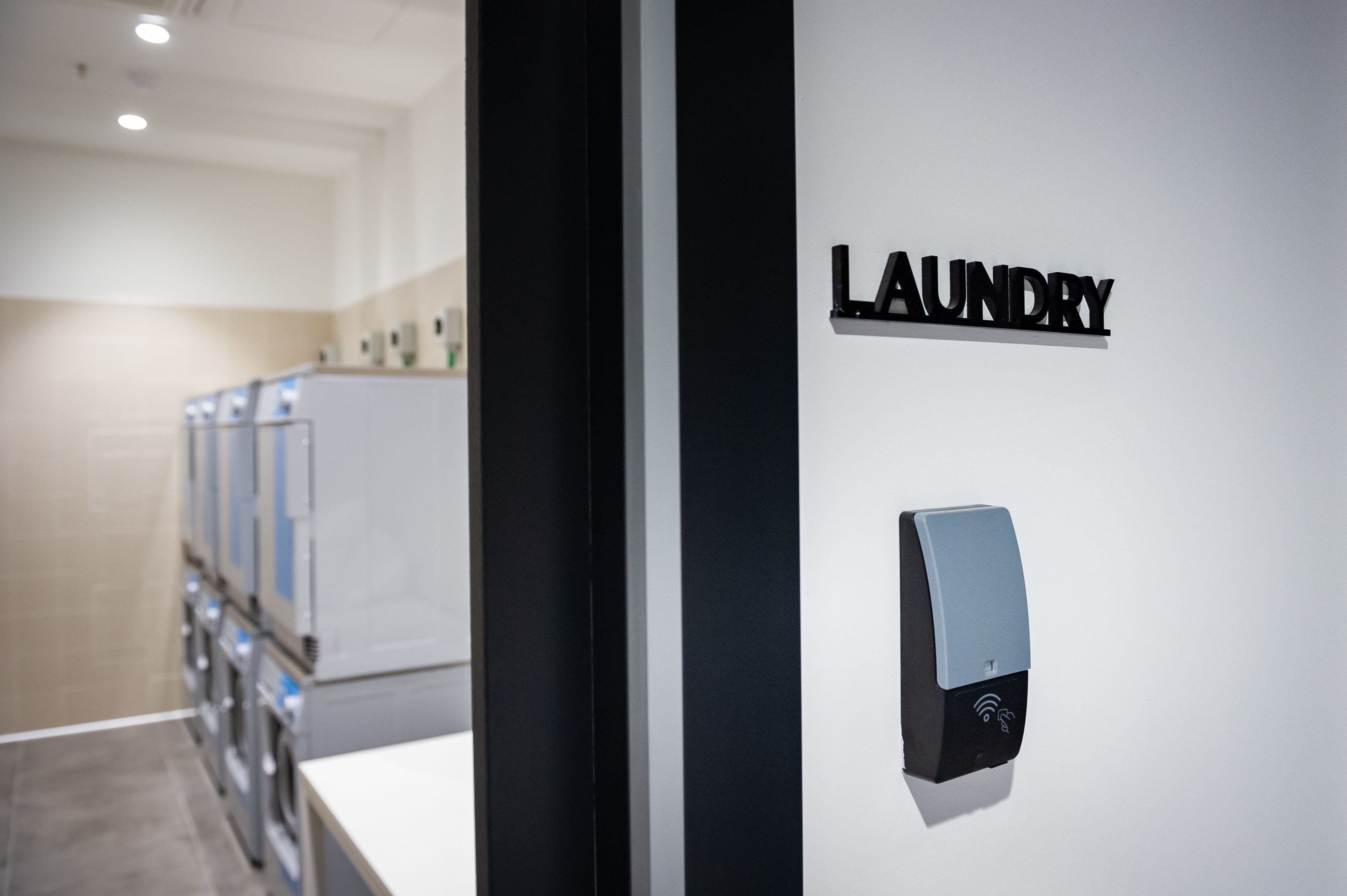 Un intérieur moderne avec une enseigne indiquant « LAUNDRY » et un appareil fixé au mur, probablement un capteur ou un panneau de commande.