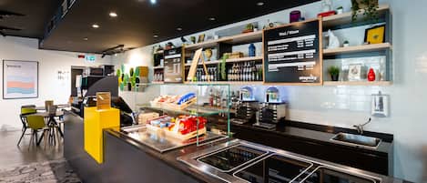 Un bar moderno con una pizarra de menú, estantes llenos de botellas y una zona de estar con sillas.