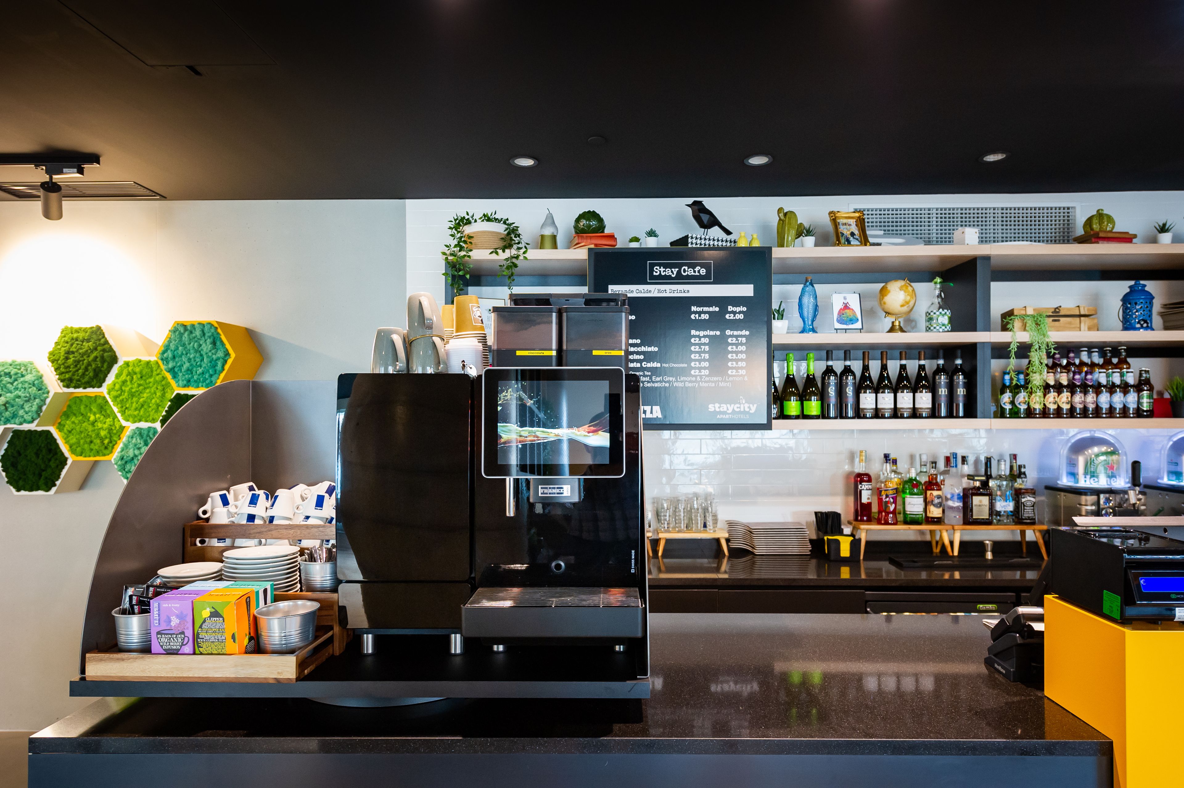 Una cafetería moderna con una máquina de café, un menú y estantes con diversos artículos.