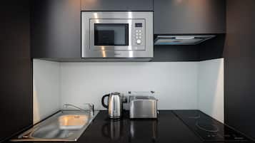 A modern kitchen with a built-in microwave, toaster, kettle, and induction cooktop.