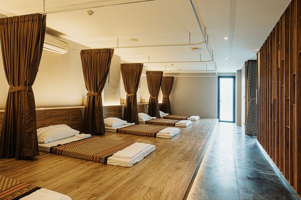 A room with multiple beds arranged in a row, each with a headboard, pillows, and towels. - Rak Elegant Hotel Patong (Patong)