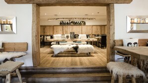 A rustic interior with wooden beams, a central seating area with a bench and stools, and shelves with decorative items. - Hubertus Mountain Refugio Allgäu (Balderschwang)