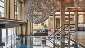 A modern lobby with a glass elevator, wooden interior, and large spherical light fixtures. - Hubertus Mountain Refugio Allgäu (Balderschwang)
