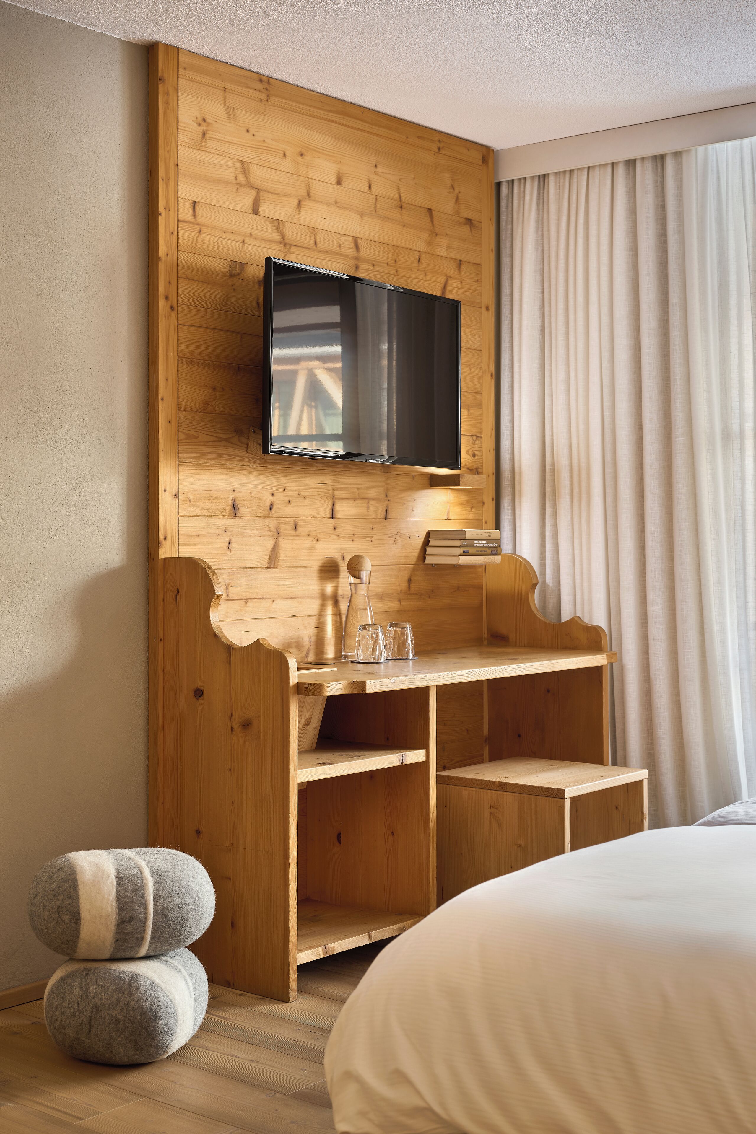 A wooden bunk bed with a TV mounted on the wall above.