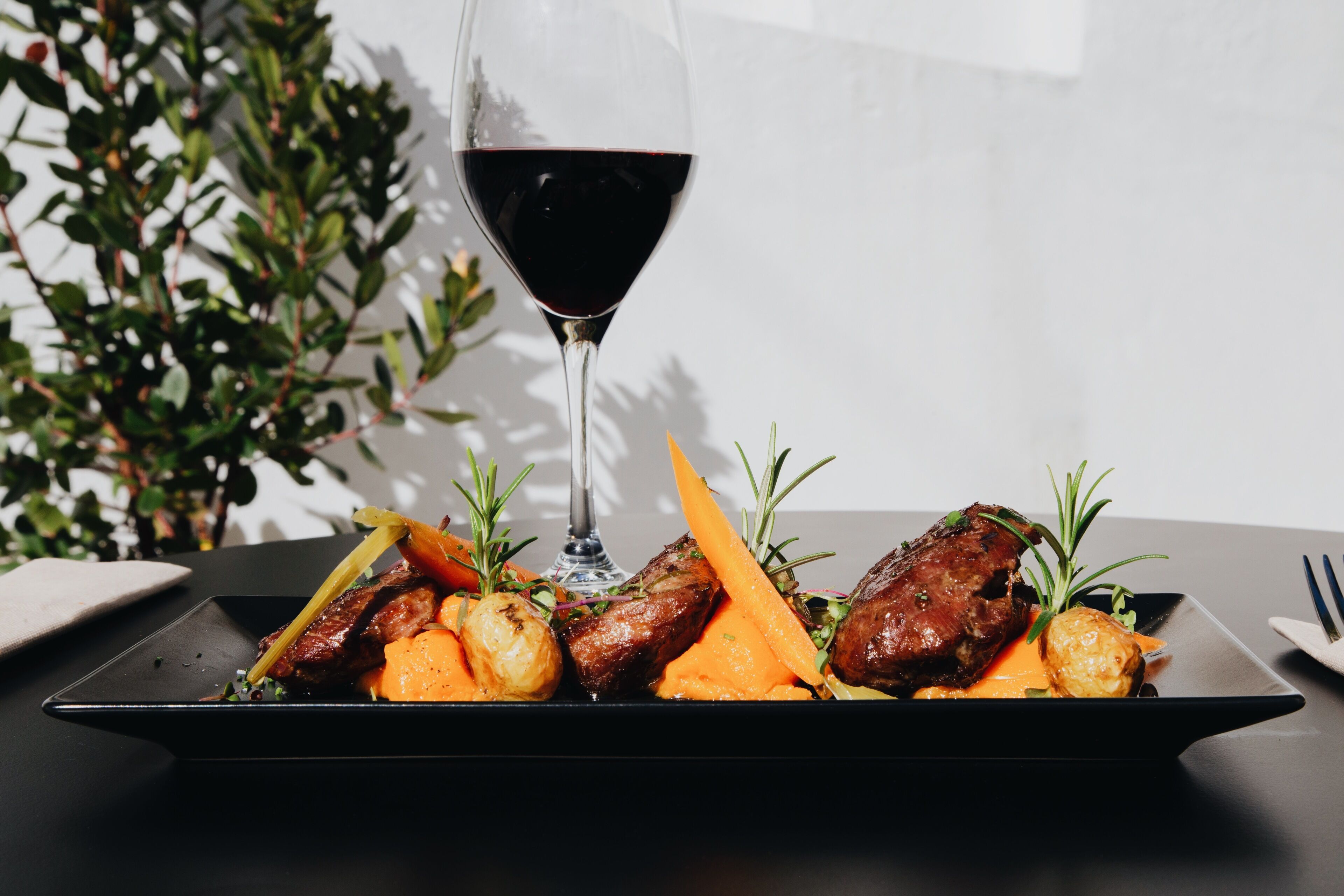 Un plato de comida con una copa de vino tinto.