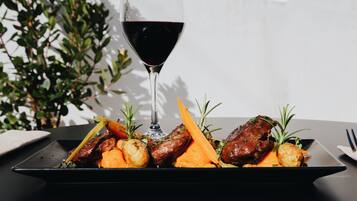 Un plato de comida con una copa de vino tinto.