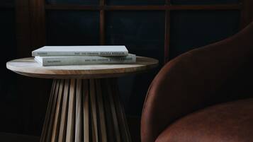 Una mesa de madera redonda con una pila de libros con los títulos "NORRANNA FOSTER" y "EXHIBITION".