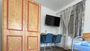 A room with a bed, a desk with two chairs, a TV, and a wardrobe. - ZV-Scholtz Gästehaus Neuötting (Neuoetting)