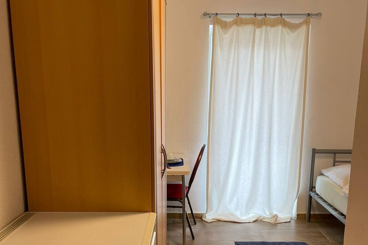 A compact room with a bed, a desk, and a chair.