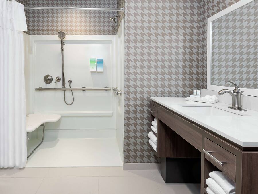 A modern bathroom with a shower, a vanity with a sink, and a mirror.