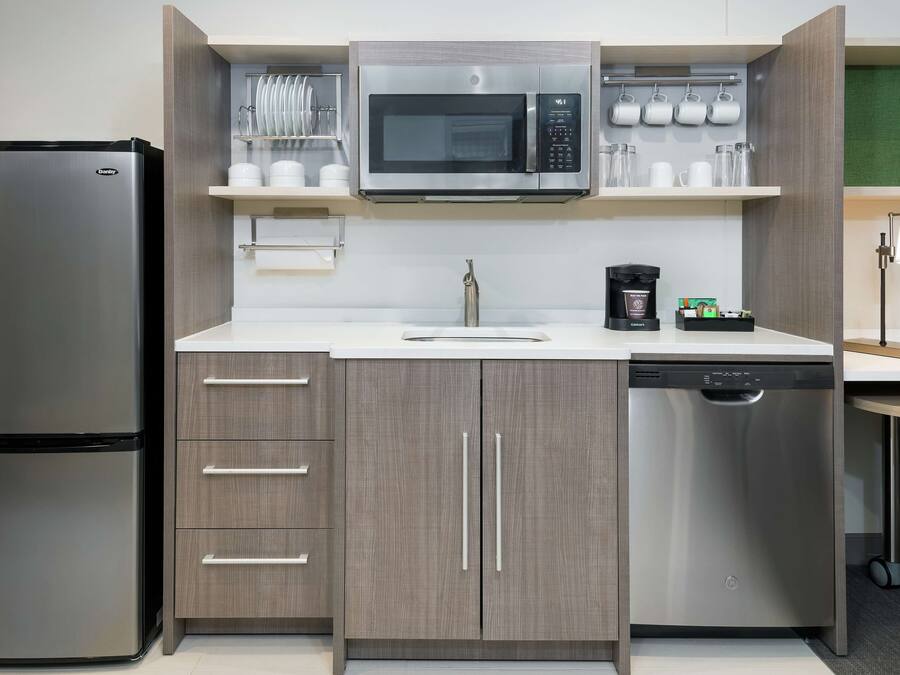A compact kitchen with a stainless steel refrigerator, a microwave, and a dishwasher.