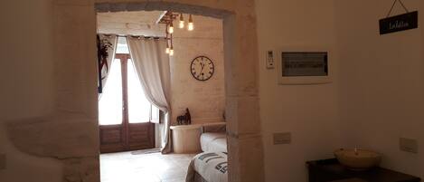 A rustic room with a wooden door, a clock, and a sign indicating the toilet.