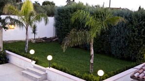 A landscaped garden with a concrete pathway, palm trees, and a hedge. - Bed and Breakfast Piano Del Re (Partinico)