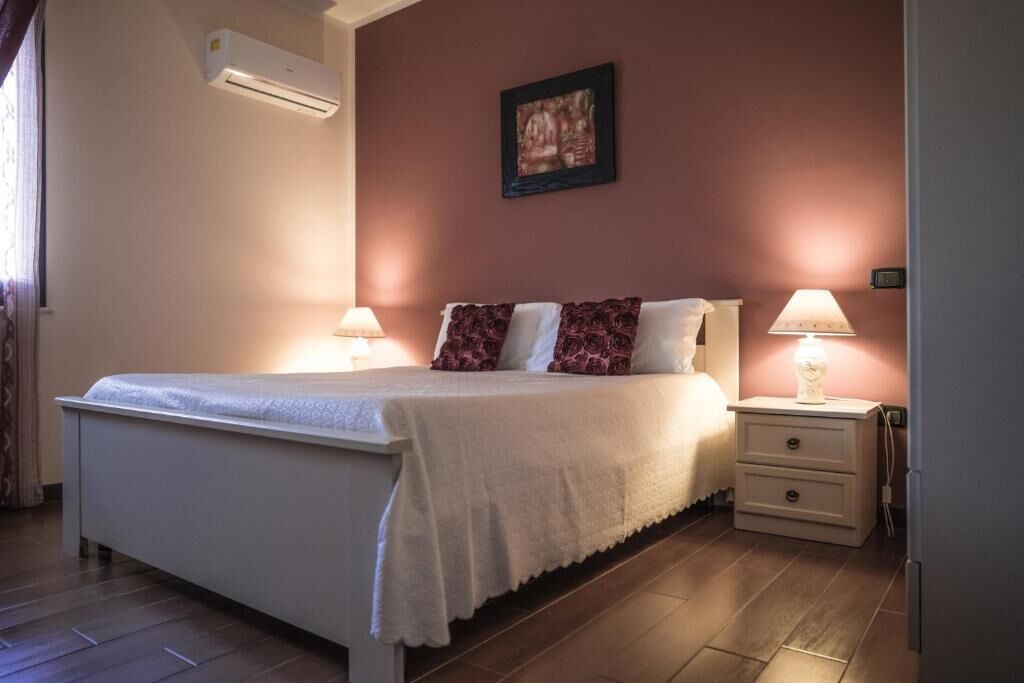 Ein Schlafzimmer mit einem Bett, Nachttischlampen, einem Beistelltisch und einer Klimaanlage.
