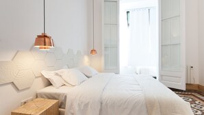 A modern bedroom with a large bed, a wooden nightstand, and two pendant lights. - La Casa de Antonio Boutique Rooms (Barcelona)