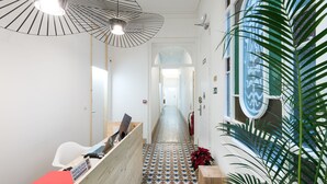 A hotel reception area with a check-in counter, a wooden desk, a patterned floor, and a large window with a decorative frame. - La Casa de Antonio Boutique Rooms (Barcelona)