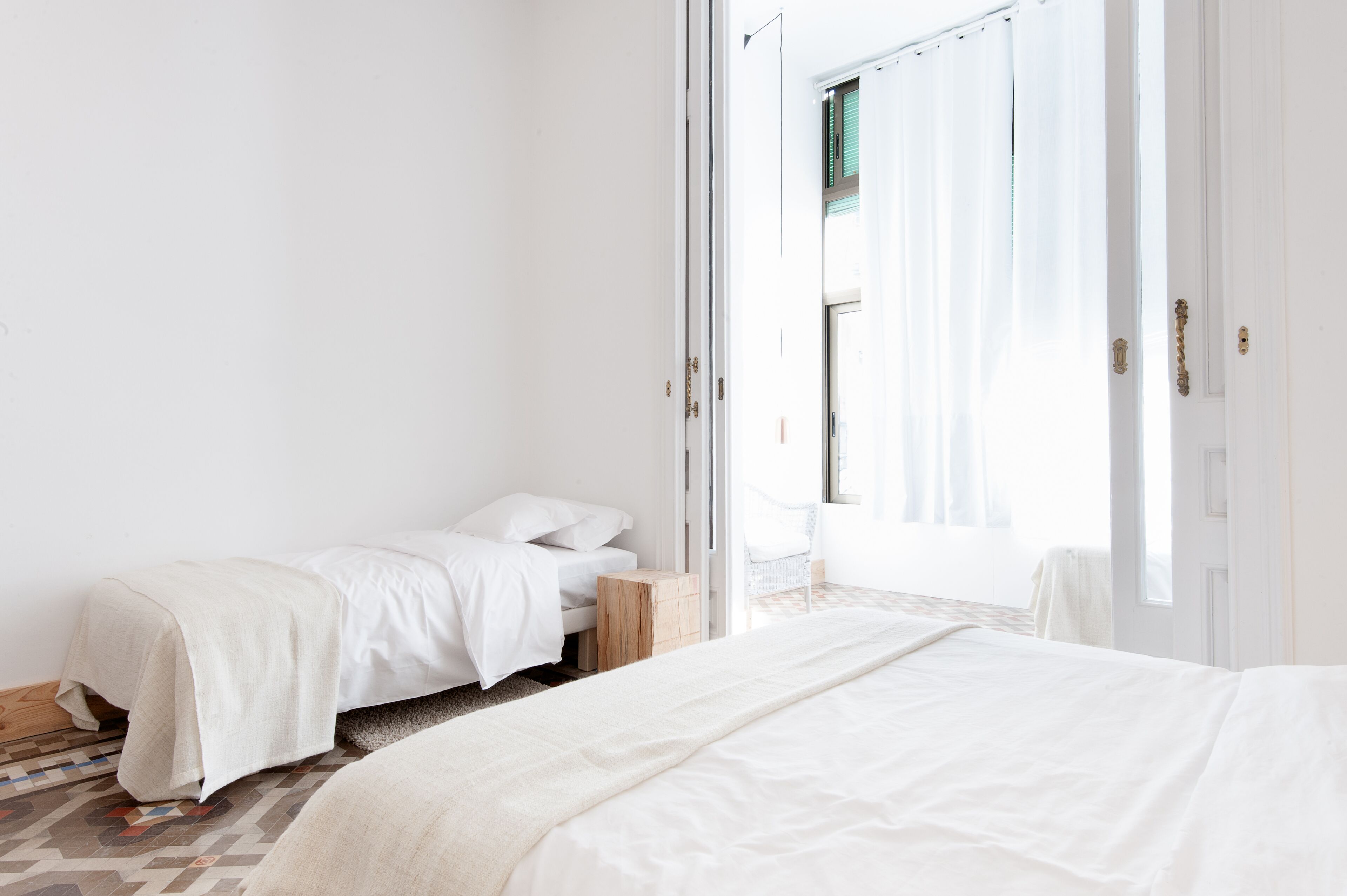 Un dormitorio con dos camas, una mesita de noche de madera y vistas a un balcón.