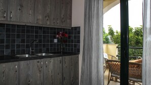 A kitchen with dark tiles, a sink, and a vase of flowers. - Elina's House (Xylokastro-Evrostina)