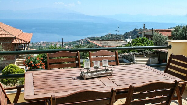 A wooden table with chairs on a balcony overlooking a coastal view. - Elina's House (Xylokastro-Evrostina)