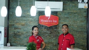 A reception desk at Meadows Inn with a stone wall background and a sign above it.
