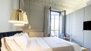 Une chambre d’hôtel avec un grand lit, un lustre moderne, une télévision et une vue sur l’extérieur.