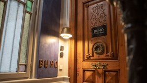 Une porte en bois avec une enseigne indiquant « BUHO BOUTIQUE ROOMS » et un heurtoir en laiton.