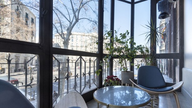 Un intérieur moderne avec un mur de verre, une table ronde, deux chaises et une plante en pot.