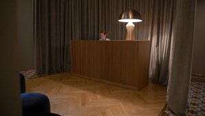 Un comptoir d’accueil avec une lampe, des panneaux en bois et un parquet à motifs en chevrons.