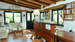 A cozy room with a wooden reception desk, a sofa, a coffee table, and a bookshelf filled with books. - Lu Pastruccialeddu (Arzachena)