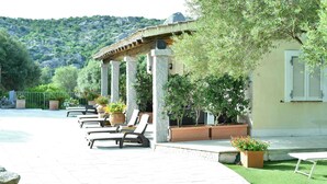 A terrace with lounge chairs, potted plants, and a pergola structure. - Lu Pastruccialeddu (Arzachena)