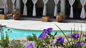 A pool area with a tiled roof, white curtains, and potted plants. - Lu Pastruccialeddu (Arzachena)