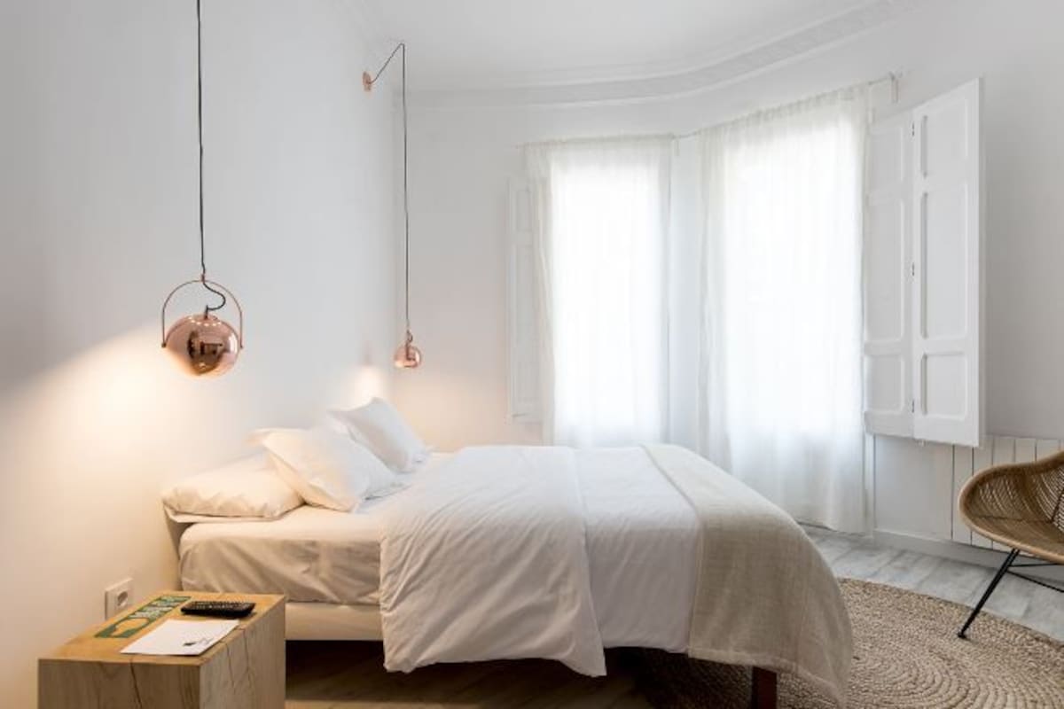 Un dormitorio moderno con cama, mesita de noche y una silla.
