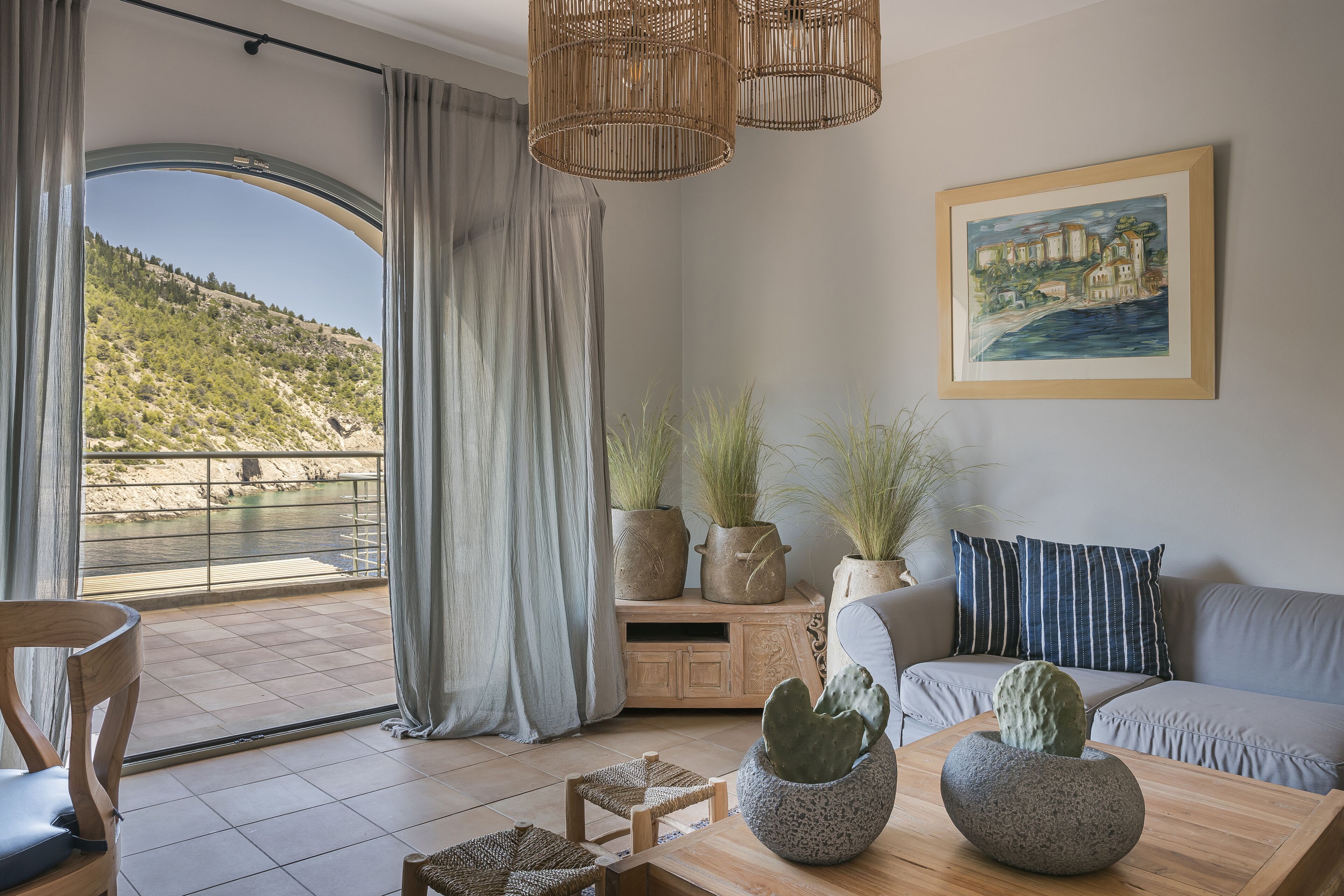 A living room with a large window, a sofa, a coffee table, and decorative plants.