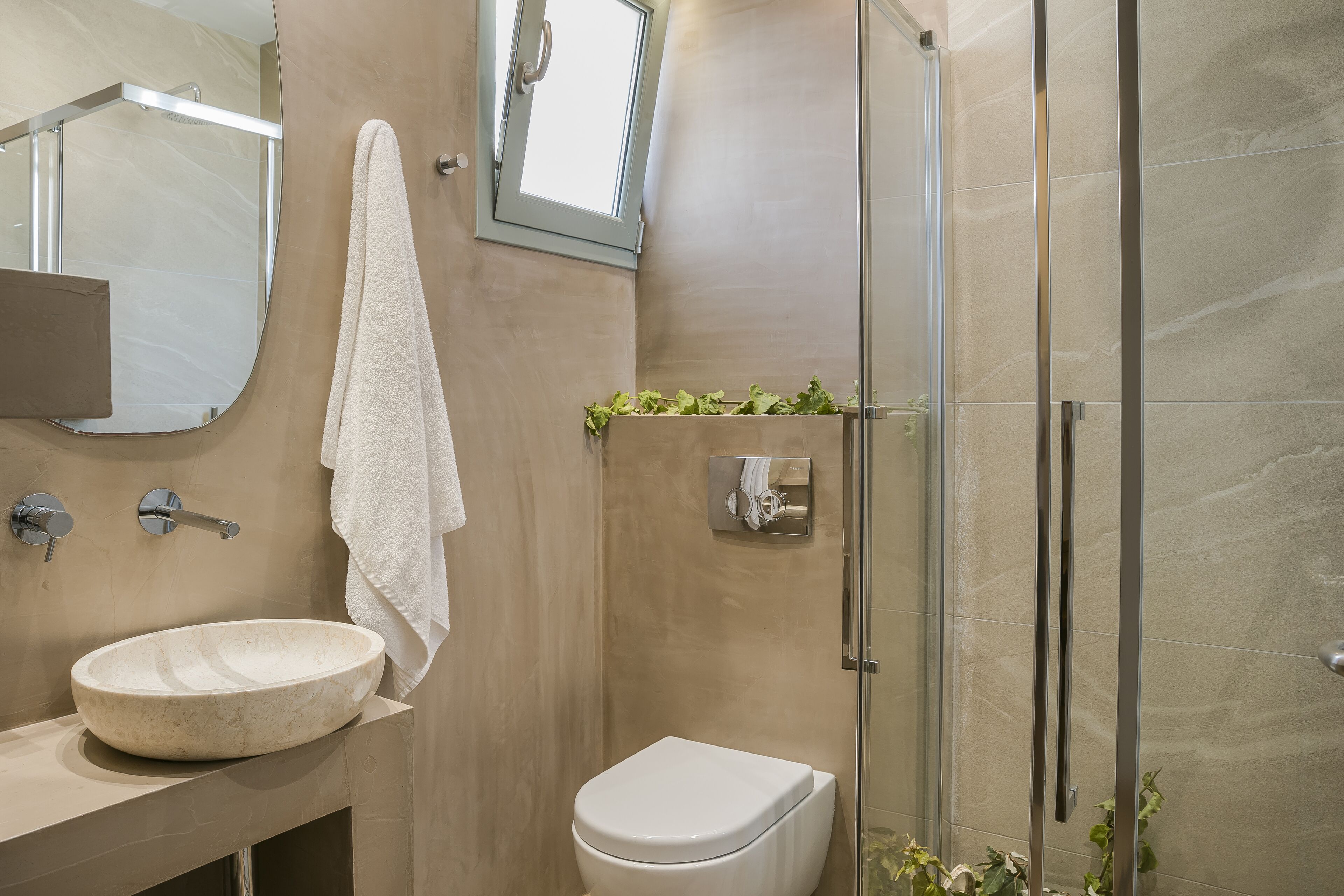 Ein modernes Badezimmer mit einem runden Waschbecken, einer Toilette und einer Duschkabine aus Glas.