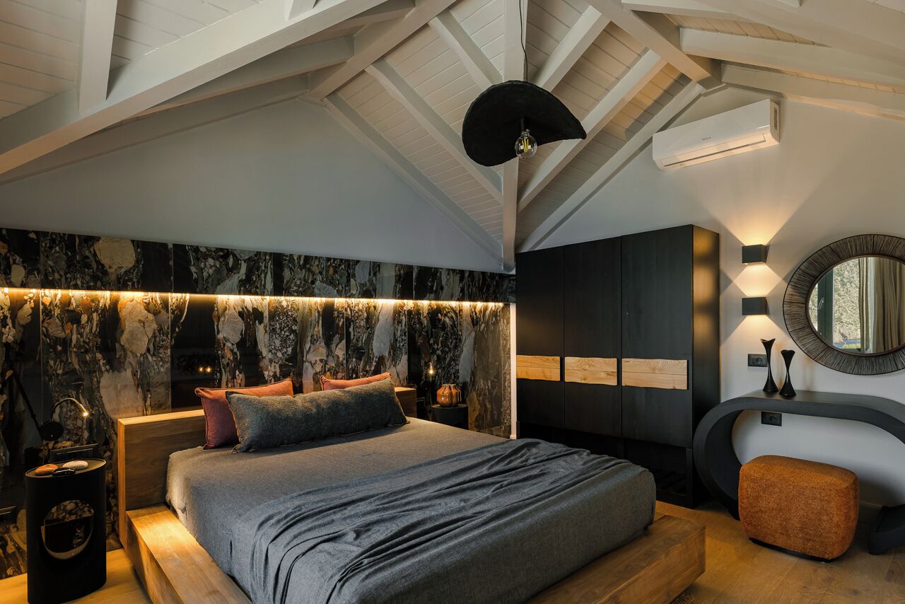Ein modernes Schlafzimmer mit einem großen Bett, einer Marmorwand und einem Dachfenster.