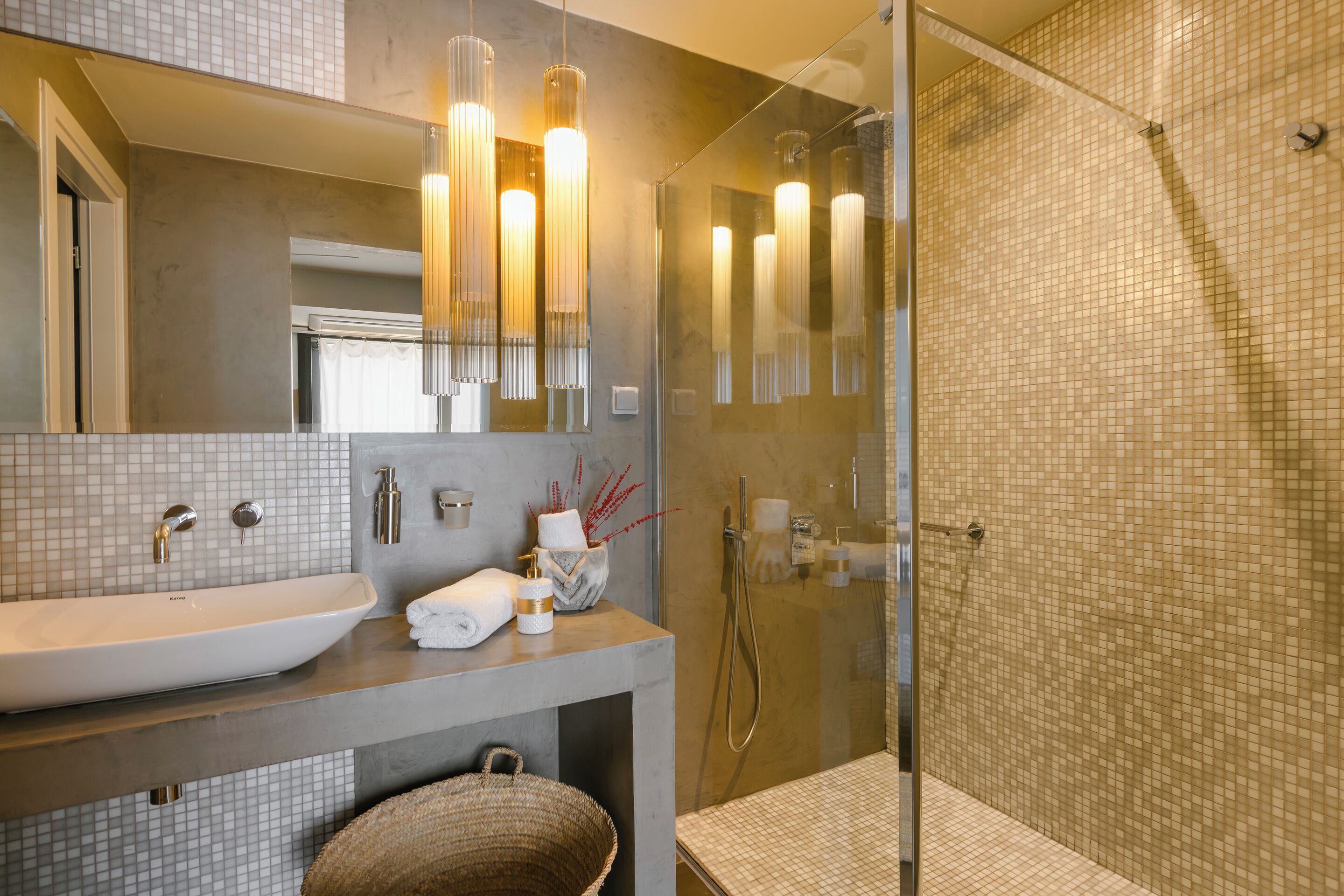 A modern bathroom with a large sink, mirror, and glass shower enclosure.