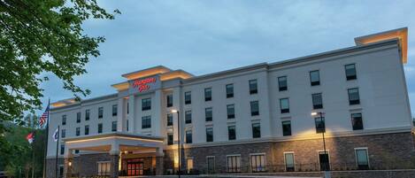 A modern hotel with a flat roof, multiple windows, and a well-lit entrance.