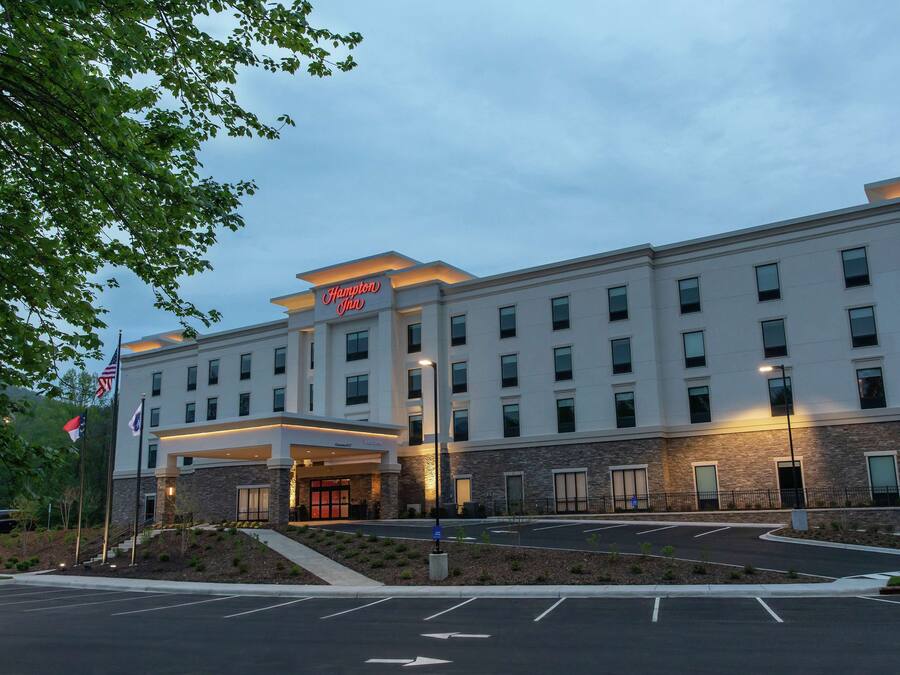 A modern hotel with a flat roof, multiple windows, and a well-lit entrance.