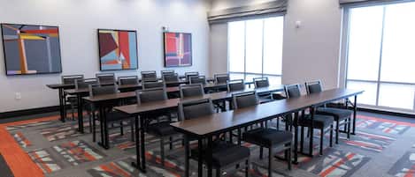 Une salle de conférence dotée d’une longue table et de chaises, de grandes fenêtres et d’œuvres d’art abstrait accrochées aux murs.