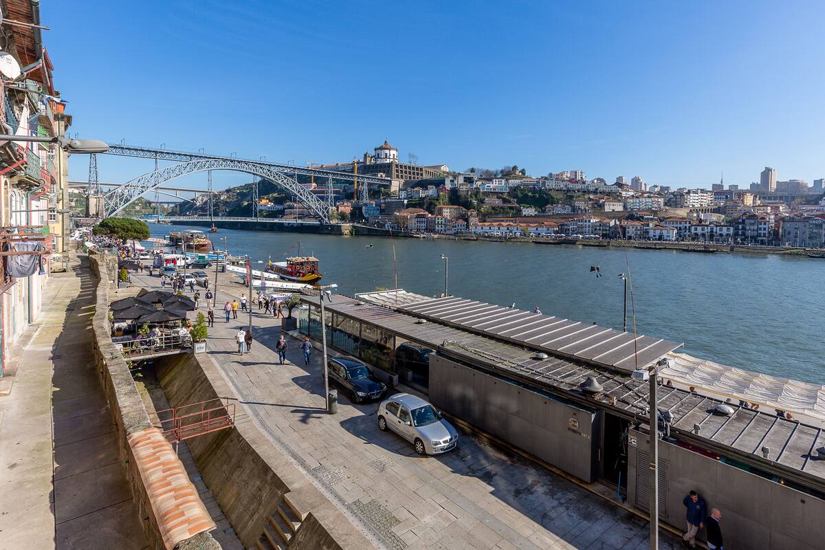 A riverside view with a bridge, buildings, and a boat dock.