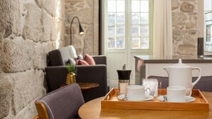 A cozy living room with a stone wall, a sofa, a coffee table, and a tray with white cups and a teapot. - YOUROPO - Ribeira Porto (Porto)