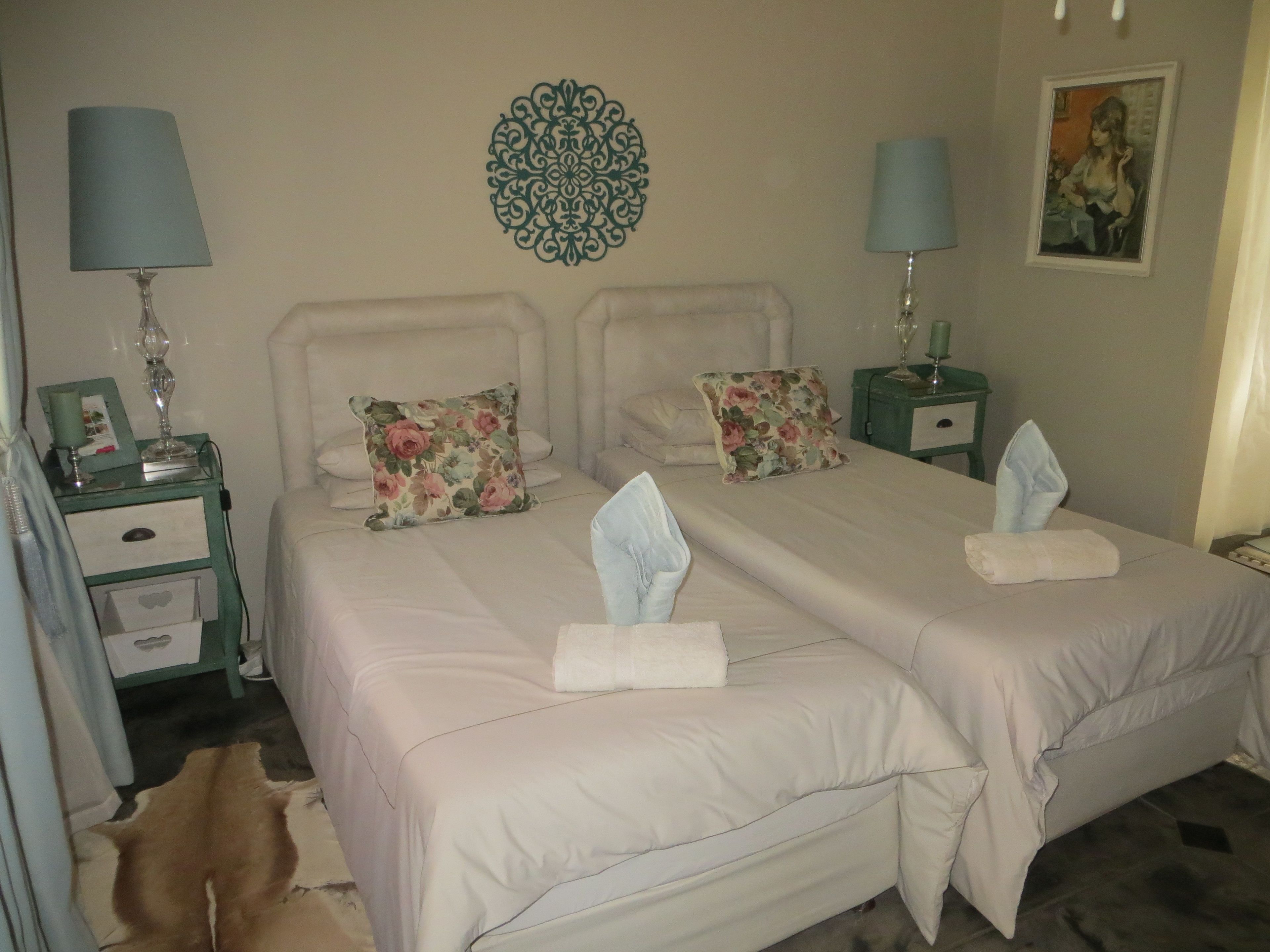 Una cama doble con almohadas florales, un adorno de pared y lámparas de noche.