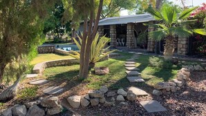 Una casa de piedra con un patio de piedra, una piscina y un jardín con un camino de piedra.