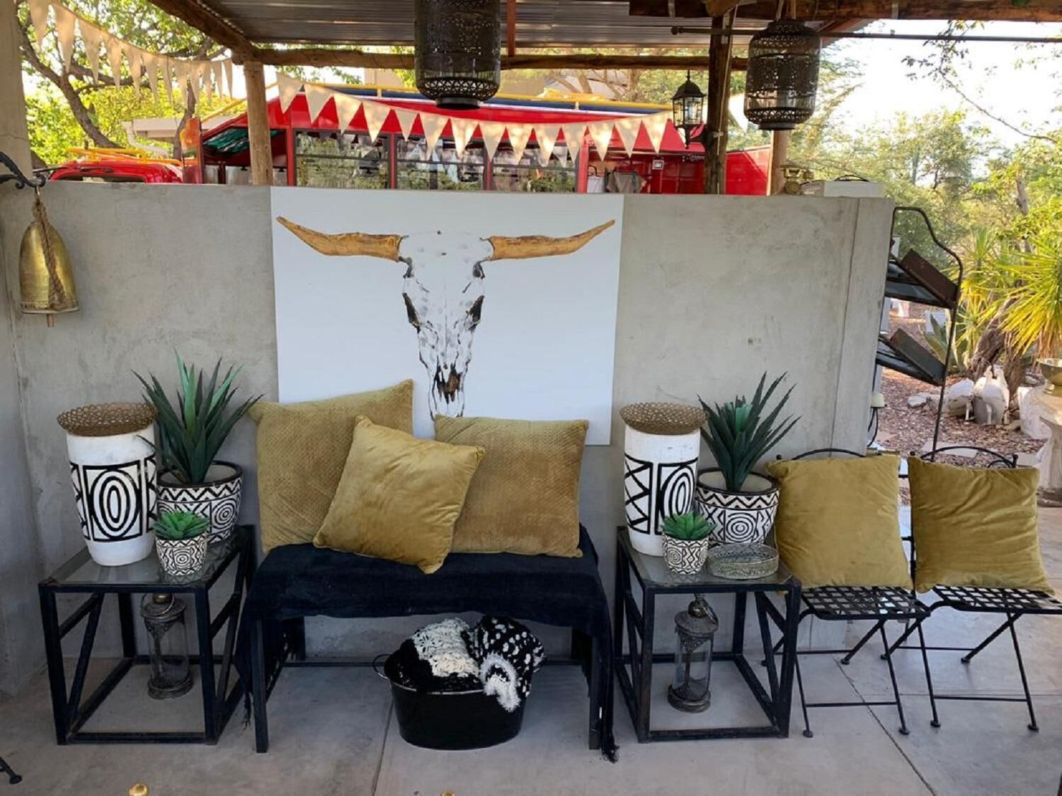 A cozy outdoor seating area with a sofa and two side tables, each with patterned vases and a lantern.