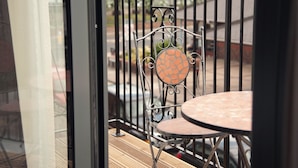 A balcony with a metal chair and table, a wooden deck, and a view of the street and buildings. - The Burlington Hotel (Cleethorpes)