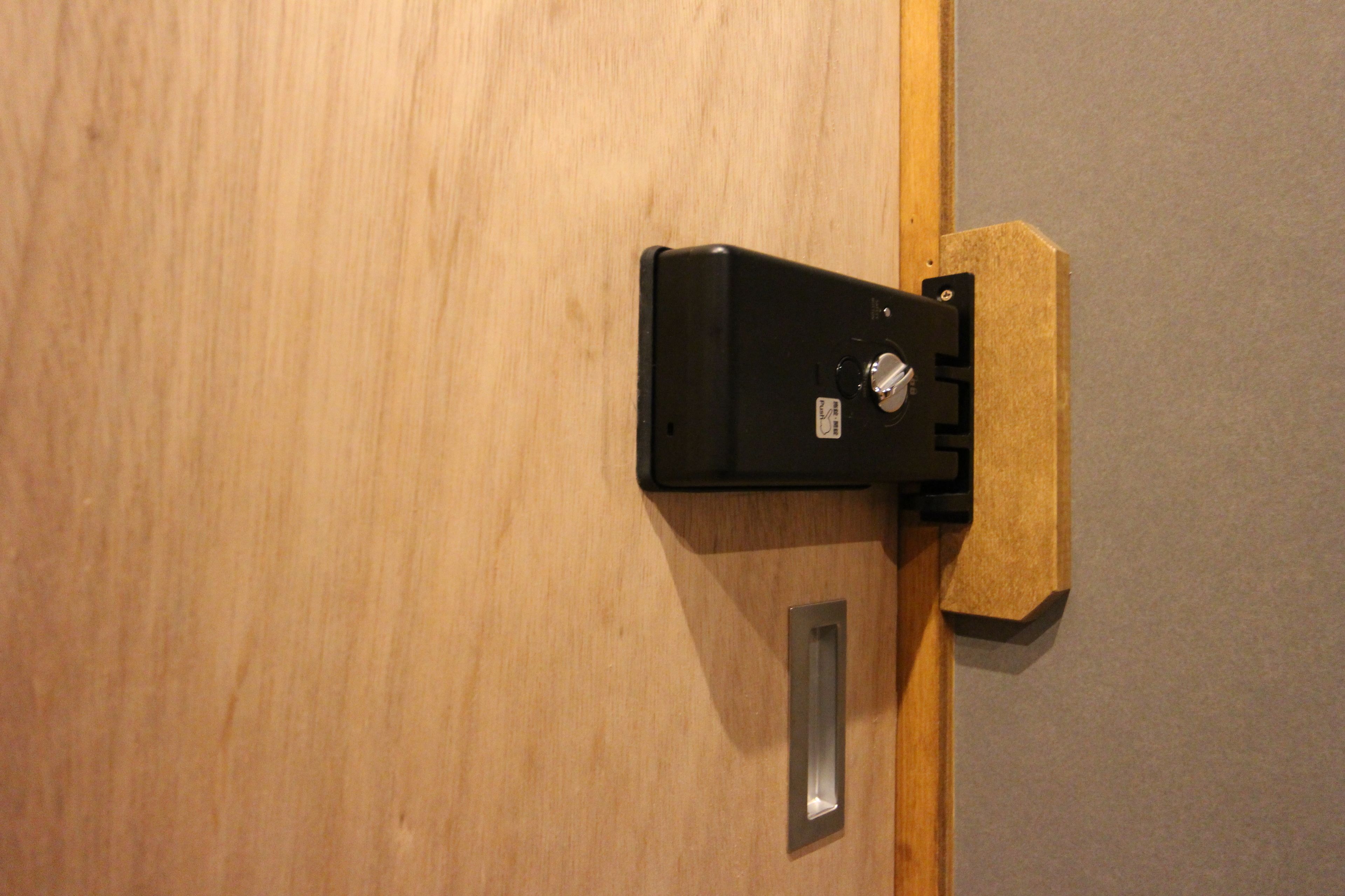 A wooden door with a black handle and a metal plate.