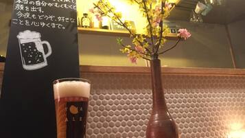 Un verre de bière à côté d’un vase rempli de fleurs, posé sur le comptoir d’un bar.