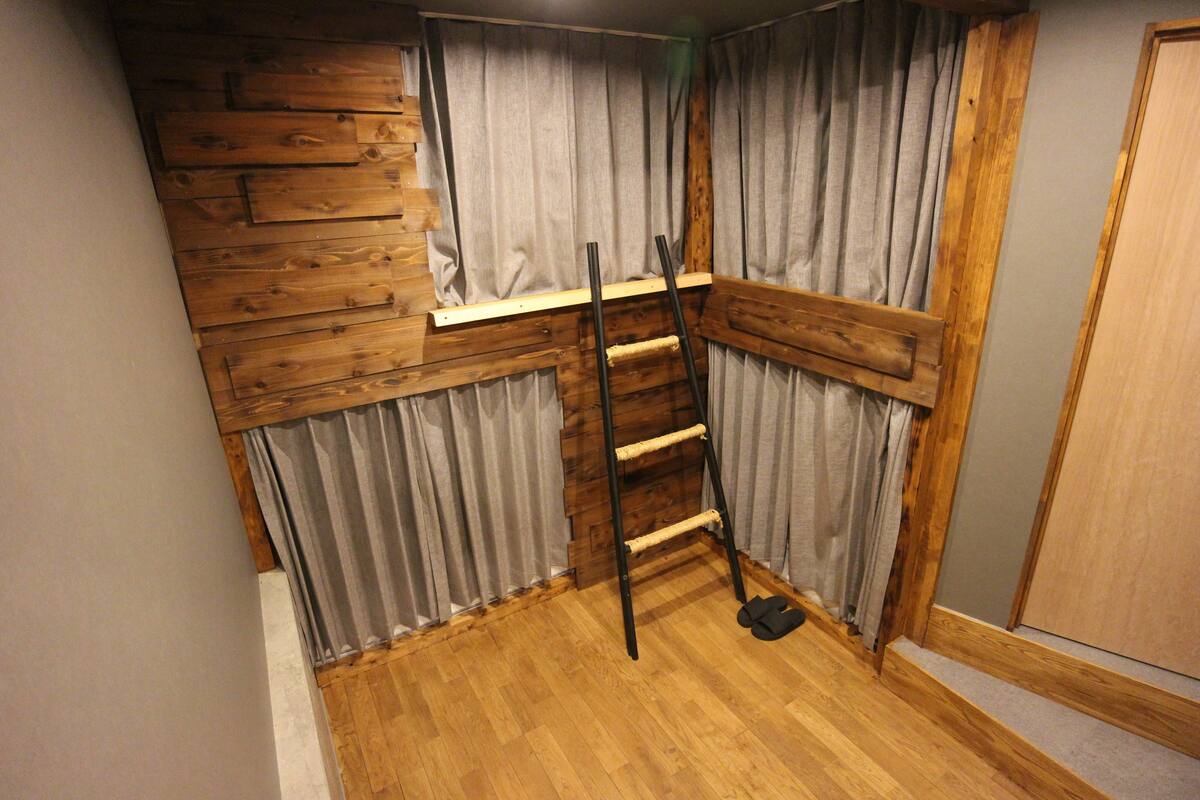 Habitación de esquina con pared y escalera de madera, además de una puerta.